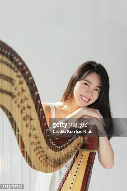 portrait of smiling female harpist while holding her harp - klassisk musiker bildbanksfoton och bilder