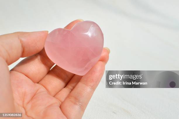 woman holding a rose quartz crystal heart - rose quartz stock pictures, royalty-free photos & images