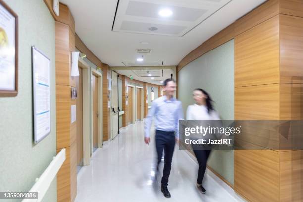 blurred people walking in hospital corridor - busy hospital lobby stockfoto's en -beelden