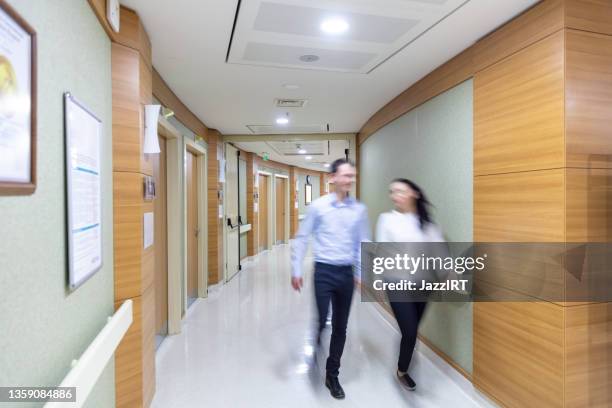 blurred people walking in hospital corridor - busy hospital lobby stock pictures, royalty-free photos & images