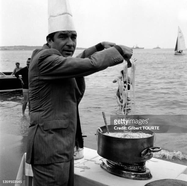 Acteur italien Ugo Tognazzi prépare des Spaghettis face à la mer lors du Festival de Cannes en mai 1964