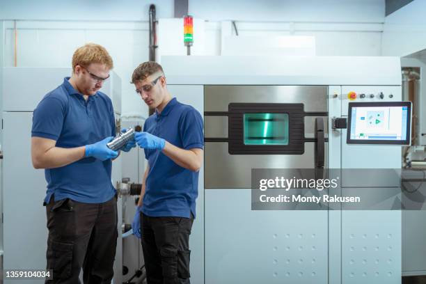 men holding metal 3d printed objects in laboratory - blue glove foto e immagini stock