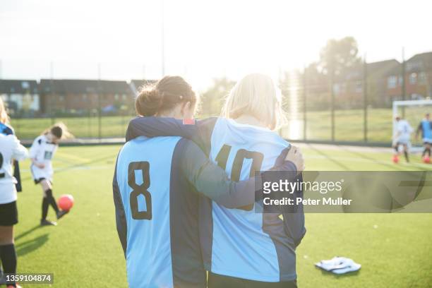 uk, rear view of female soccer team members embracing in field - local soccer field stock pictures, royalty-free photos & images
