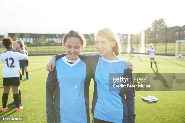 uk, portrait of female soccer team members embracing in field - fußballtrikot stock-fotos und bilder