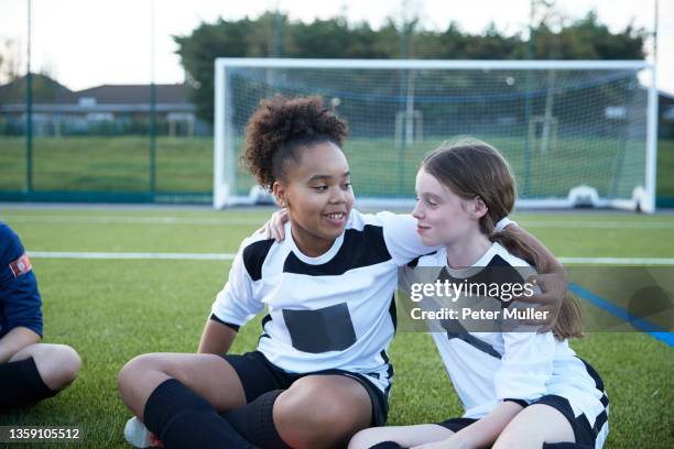 uk, female soccer team members embracing in field - fußballtrikot stock-fotos und bilder