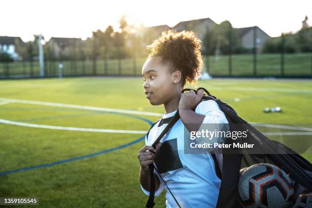 uk, rear view of female soccer player carrying bag with balls in field - girls football stockfoto's en -beelden