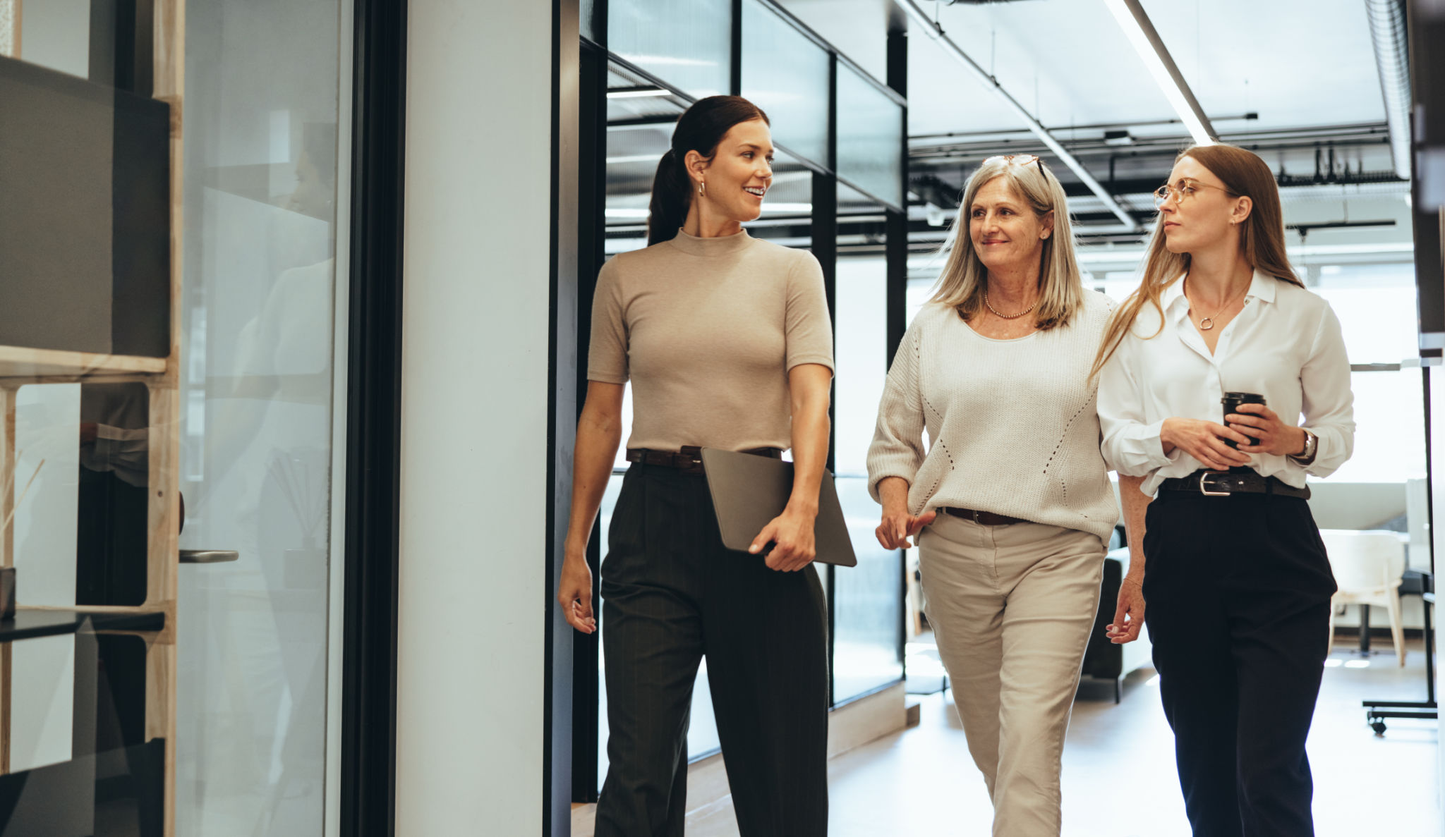 Three businesswomen walking together in an office Three businesswomen walking together in an office