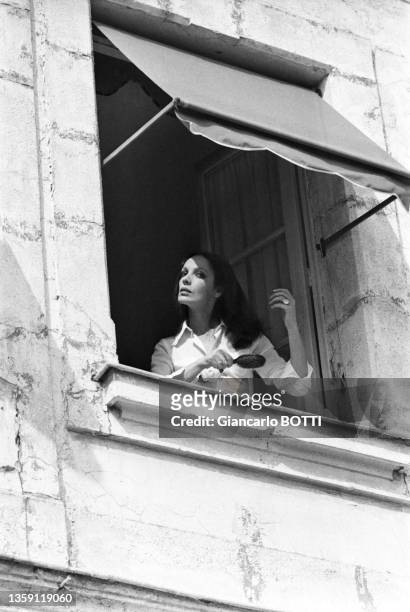 Marie Laforêt se brosse les cheveux avec un peigne à une fenêtre sur le tournage du film 'Le petit poucet' réalisé par Michel Boisrond en 1972, France