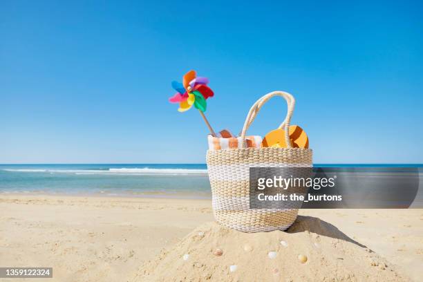 still life of beach bag and colorful pinwheel at sea against blue sky - beach bag stockfoto's en -beelden