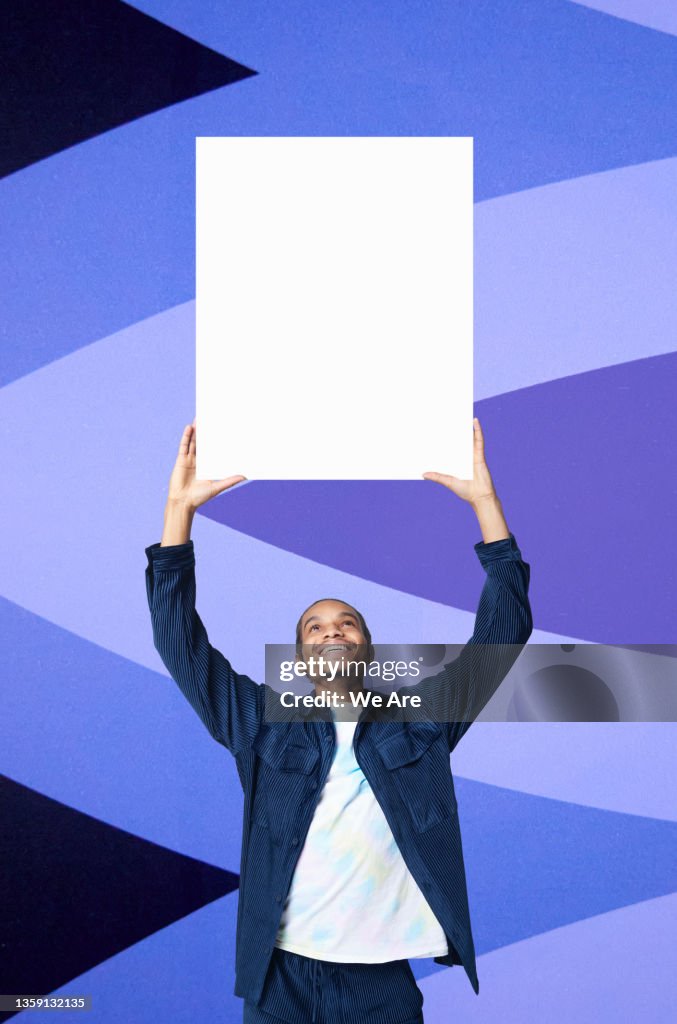 Young Man holding blank placard on colourful background