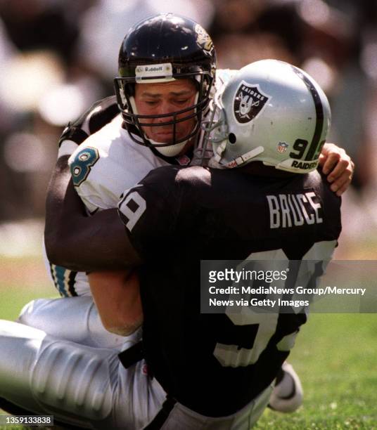 Raiders defensive end Aundray Bruce wraps up Jaquars quarterback Mark Brunell during second quarter action .