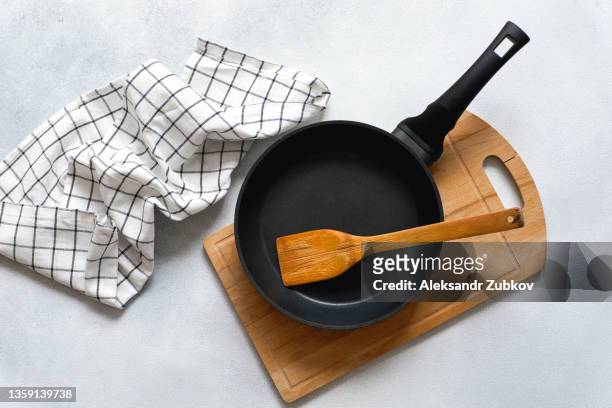 a new clean empty cast-iron frying pan and a wooden spatula, on a cutting board. the concept of cooking in a restaurant and cafe, at home in the kitchen. cook yourself, taking courses on the ability to cook delicious and beautiful food. - braadpan stockfoto's en -beelden