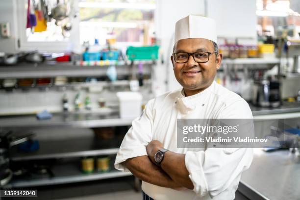 an indian chef standing in his kitchen - indian chef stock pictures, royalty-free photos & images