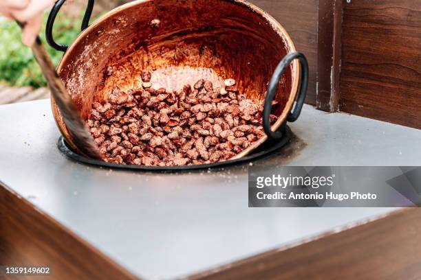 vendor cooking sugared almonds in a street stall. - almond caramel stock pictures, royalty-free photos & images