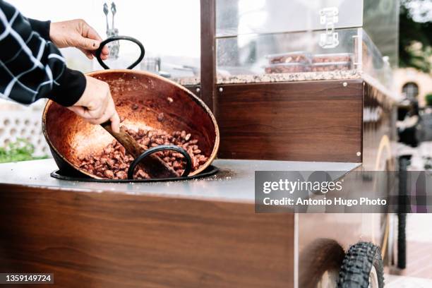 vendor cooking sugared almonds in a street stall. - burnt cookies stock-fotos und bilder