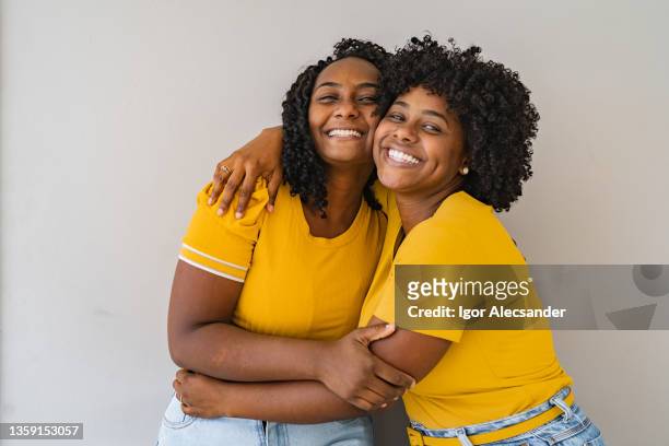 portrait of two sisters hugging each other smiling - black blouse stock pictures, royalty-free photos & images