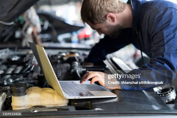 mechanic using laptop car diagnostic at garage. - meccanismi foto e immagini stock