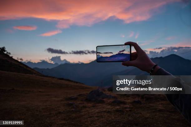 capturing a mountain sunset,cropped hand photographing mountains against sky during sunset,bielmonte,biella,italy - new discovery stock pictures, royalty-free photos & images