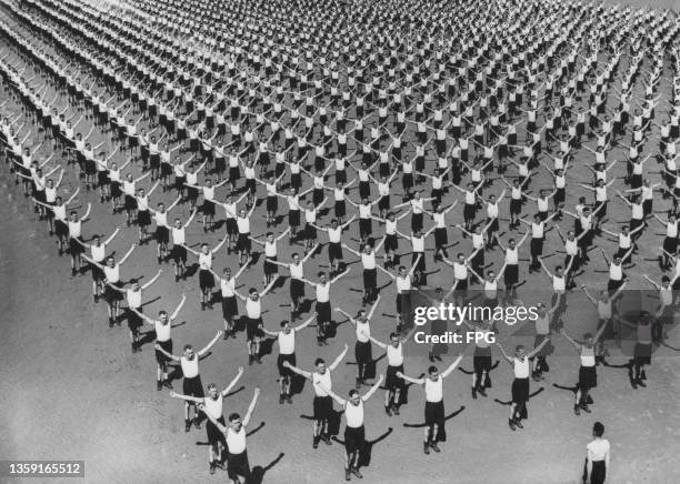 Royal Air Force physical education instructor from No10 Initial Training Wing gives aerobic exercise instructions to a large drill parade of recruits...