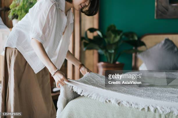 joven asiática haciendo su rutina matutina, haciendo su cama en casa. comencemos el día - decorar fotografías e imágenes de stock