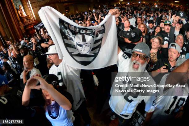 Raider fans Matt Rabalais, of Oakley, left, and Michael Clement, of Brentwood, hold a Raiders flag as they cheer with other fans during the Raider's...