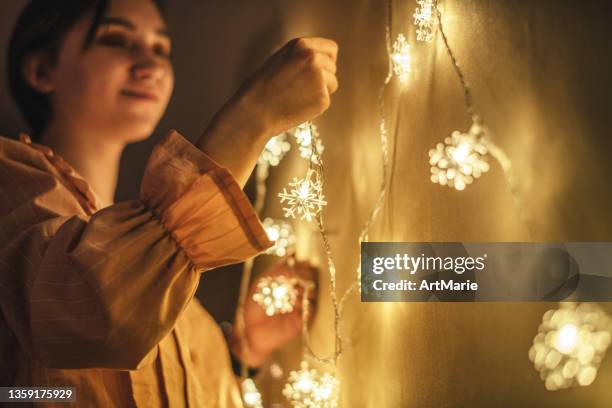 young woman decorating home for christmas - hanging christmas lights stock pictures, royalty-free photos & images