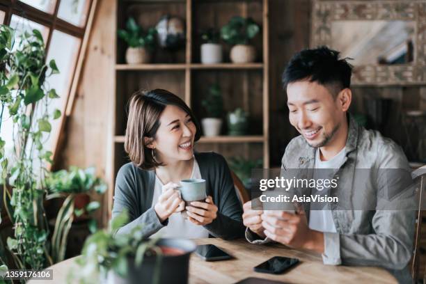 幸せな若いアジアのカップルは、カフェでコーヒーデートをし、コーヒーを飲み、おしゃべりをしています。一緒にリラックスした瞬間を楽しむ - asian and indian ethnicities ストックフォトと画像