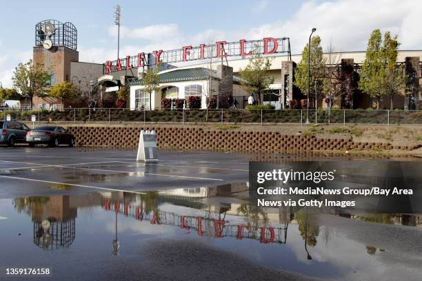 Rain puddles cover a parking lot as the Sacramento River Cats host the Oakland Athletics in an exhibition game at Raley Field in Sacramento, Calif.,...