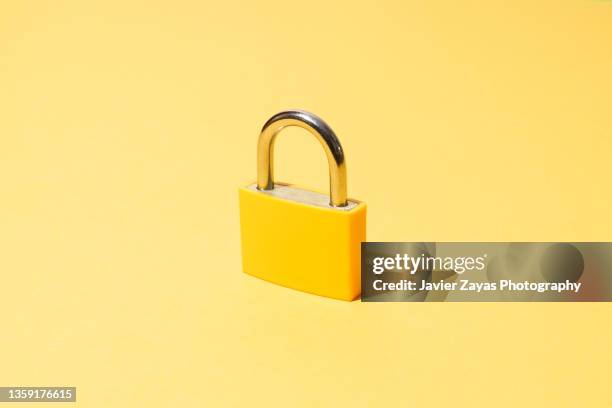yellow padlock on yellow background - vorsorge stock-fotos und bilder