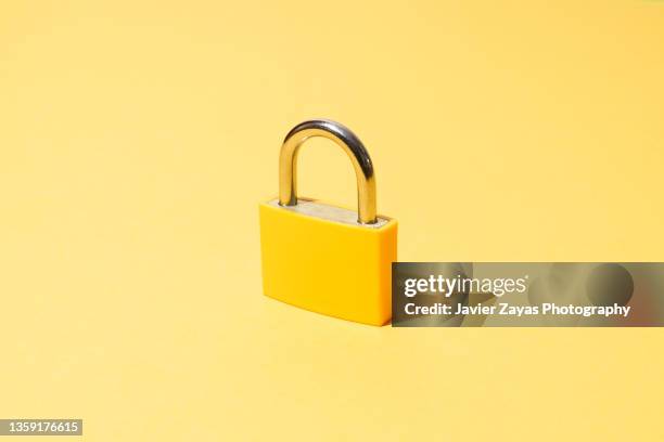 yellow padlock on yellow background - seguridad fotografías e imágenes de stock