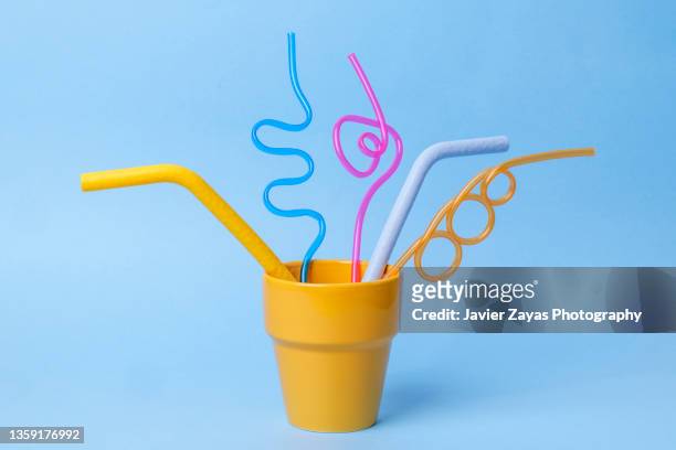 some plastic straws on blue background - pajita fotografías e imágenes de stock