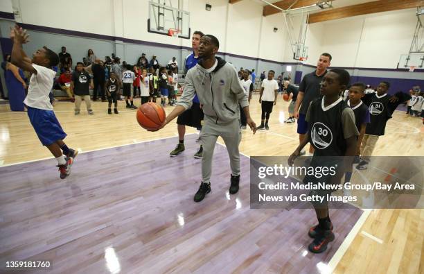 Golden State Warriors player Ian Clark, center, works with young basketball players on a refurbished court at the East Oakland Youth Development...