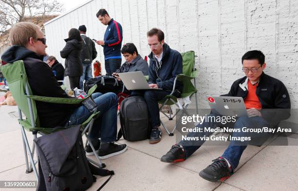 Mike Gowen, of Santa Clara, seated left, Caleb Elston, of Palo Alto, center, and Hoon Kim, of Redwood City, right, join hundreds of people as they...