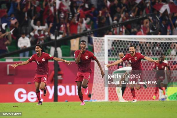 Mohammed Muntari of Qatar celebrates with teammates Homam Ahmed and Boualem Khoukhi after scoring their team's first goal during the FIFA Arab Cup...