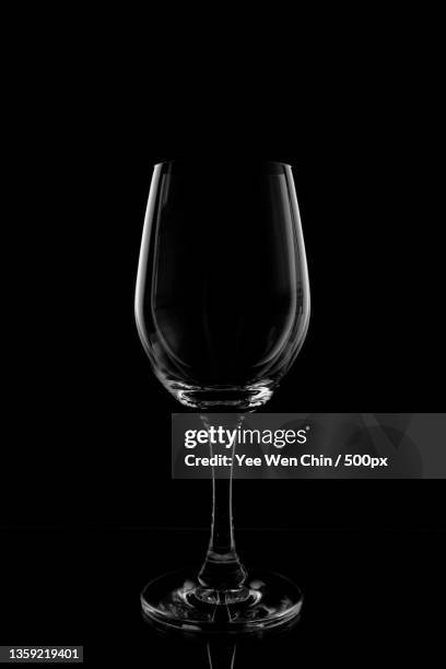 silhouette,close-up of wineglass against black background - empty wine glass stockfoto's en -beelden