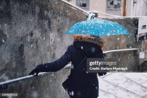 girl with umbrella goes down the staircase while it snows - sleet stock pictures, royalty-free photos & images