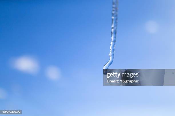 icicles and droplets photographed against a blue sky - つらら ストックフォトと画像