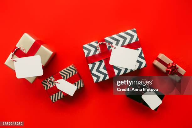 top view of bunch of gift boxes with empty labels and paper wrapping placed on red background during holiday celebration. new year celebration concept - advent calendar stock pictures, royalty-free photos & images