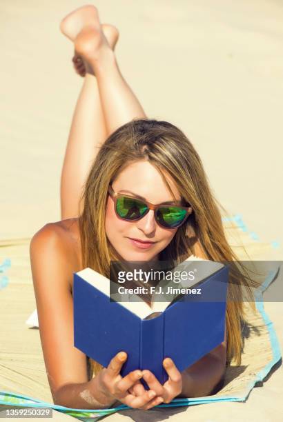 young woman reading a book on the beach - j lee fotografías e imágenes de stock