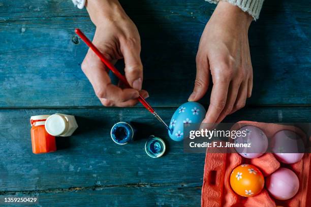 close-up of woman's hands painting an easter egg - easter egg stock-fotos und bilder