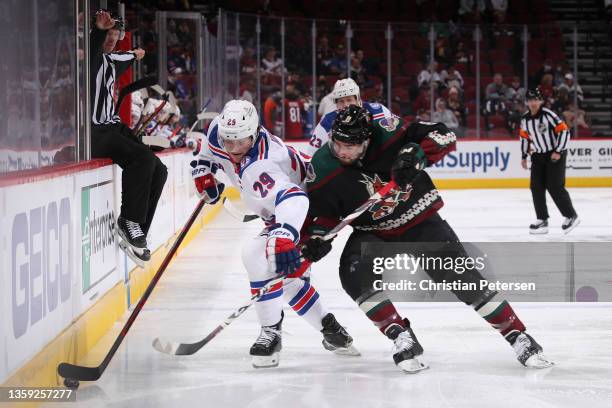 Dryden Hunt of the New York Rangers skates with the puck under pressure from Nick Schmaltz of the Arizona Coyotes during the first period of the NHL...