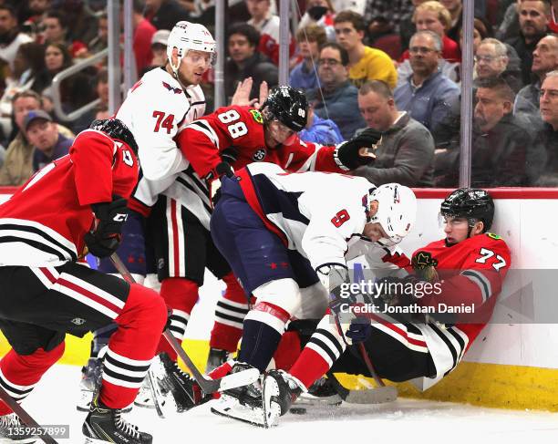 Kirby Dach of the Chicago Blackhawks is knocked against the boards and to the ice as he and teammate Patrick Kane battle for the puck with Dmitry...