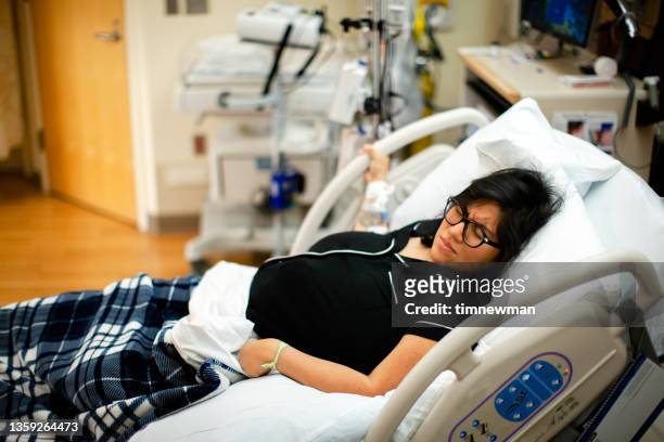 schwangere frau im krankenhausbett mit schmerzhaften wehen vor der geburt - labor childbirth stock-fotos und bilder