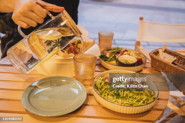 enjoying brunch with friend outdoor-pouring water into drinking glass - garlic bread stock pictures, royalty-free photos & images