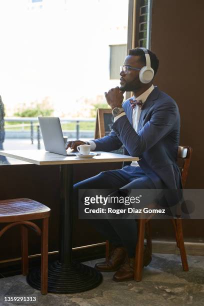 side view of young businessman working from his laptop at a restaurant in the city. - african creative with laptop working outside stock-fotos und bilder