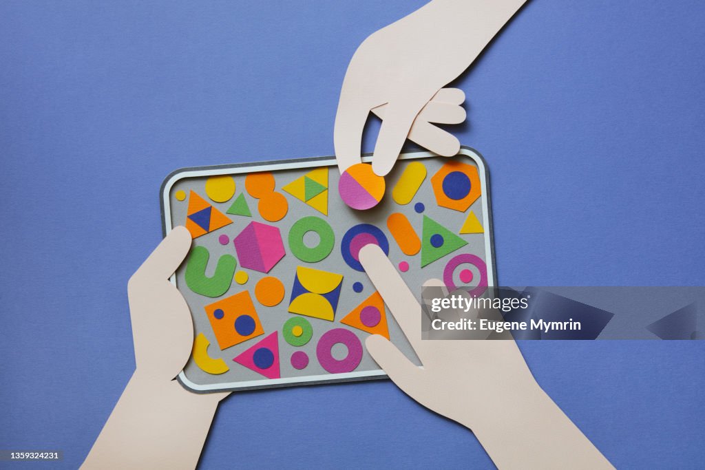 Hands holding digital tablet with multi colored geometric shapes