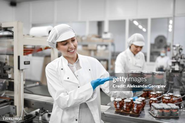 arbeiterin zeigt chia puddinggläser verpackt und bereit für den verkauf in der fabrik - same person different outfits stock-fotos und bilder