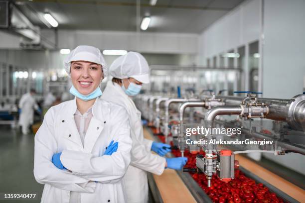 female worker displaying confidence at job position in factory making peppers with cottage cheese - food processing plant stockfoto's en -beelden