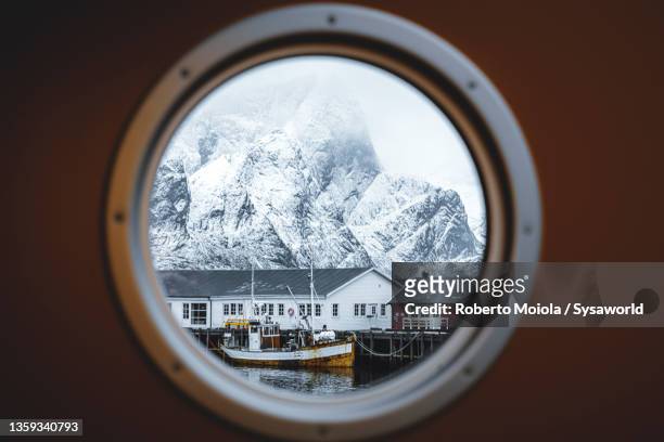 rorbu and snowy mountains view from ferry, norway - patrijspoort stockfoto's en -beelden