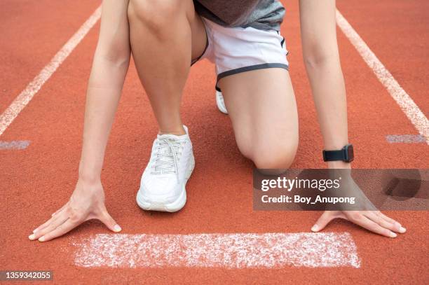 cropped shot view of athlete female runner in start position ready for sprint at the running track in stadium. - challenge launch stock pictures, royalty-free photos & images